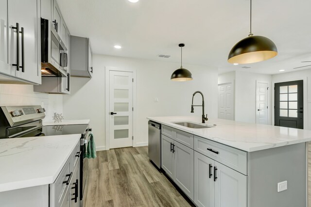 kitchen with sink, decorative light fixtures, a kitchen island with sink, gray cabinets, and appliances with stainless steel finishes