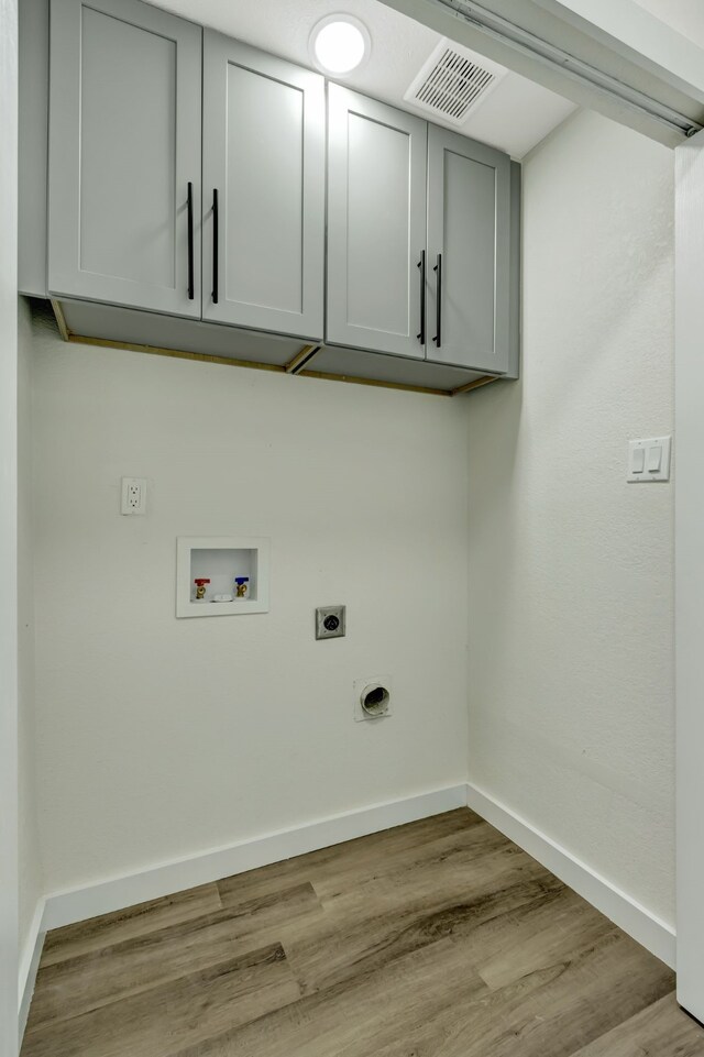 laundry area featuring hookup for a washing machine, light hardwood / wood-style flooring, electric dryer hookup, and cabinets