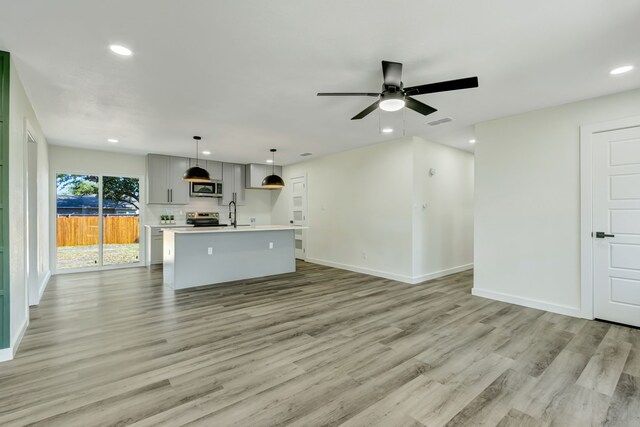 unfurnished living room featuring light hardwood / wood-style floors, sink, and ceiling fan