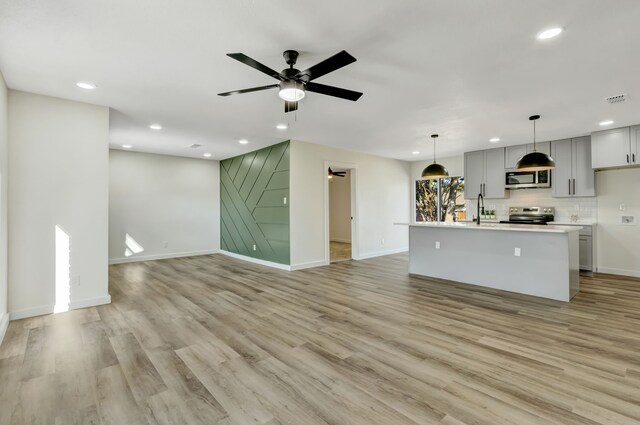 unfurnished living room with ceiling fan, sink, and light hardwood / wood-style floors