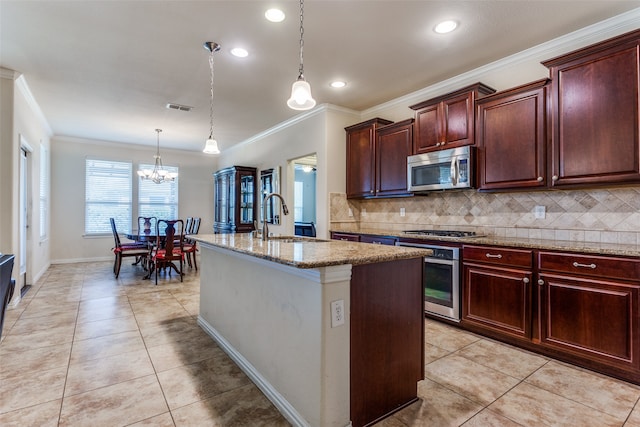 kitchen featuring ornamental molding, a center island with sink, appliances with stainless steel finishes, pendant lighting, and sink