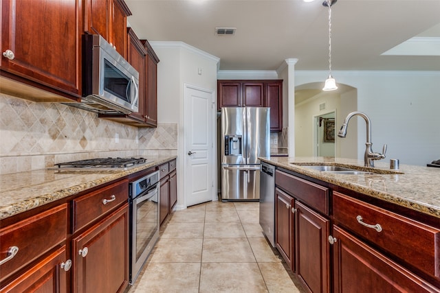 kitchen featuring sink, light stone counters, appliances with stainless steel finishes, ornamental molding, and pendant lighting