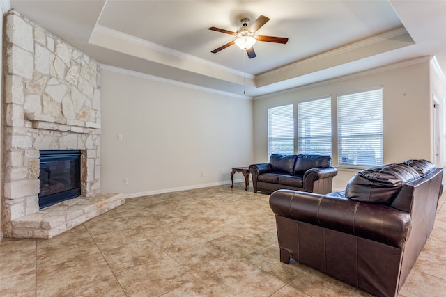 tiled living room featuring ornamental molding, a fireplace, ceiling fan, and a tray ceiling