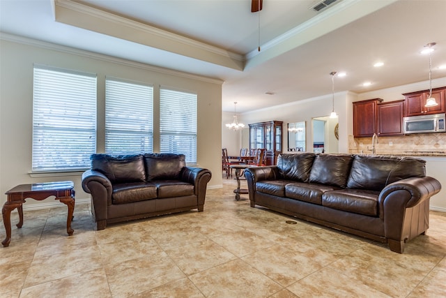 living room with a raised ceiling, an inviting chandelier, and ornamental molding