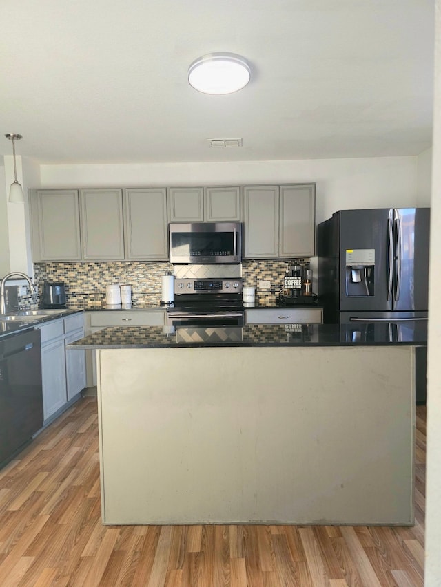 kitchen with tasteful backsplash, black appliances, sink, light hardwood / wood-style floors, and decorative light fixtures