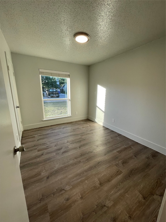 empty room with a textured ceiling and dark wood-type flooring