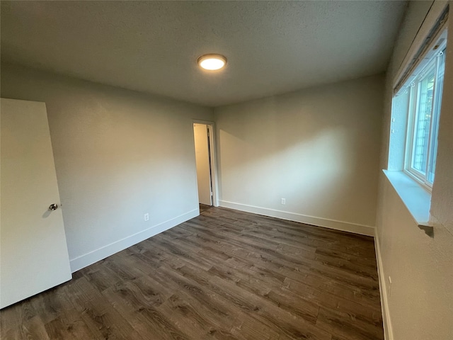 empty room featuring a textured ceiling and dark wood-type flooring