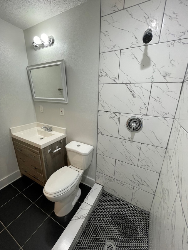 bathroom with vanity, toilet, tiled shower, a textured ceiling, and tile patterned flooring