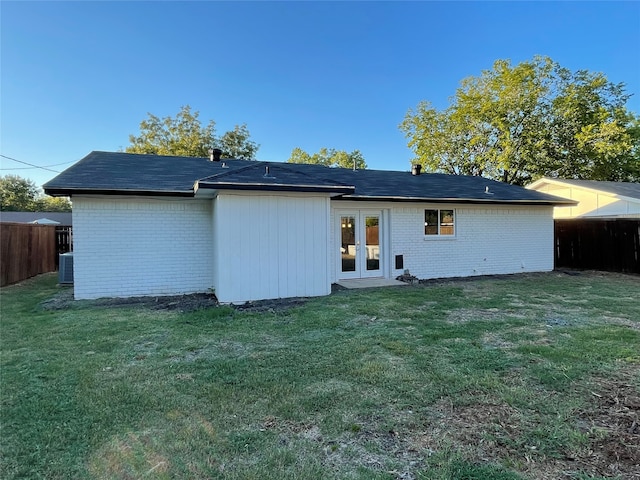 rear view of property featuring a yard, central air condition unit, and french doors