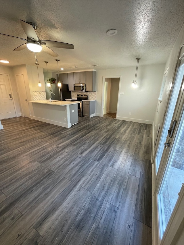 unfurnished living room with a textured ceiling, dark hardwood / wood-style floors, and ceiling fan