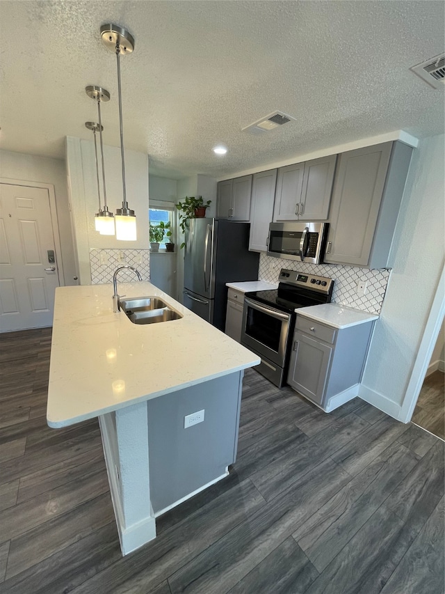 kitchen featuring sink, decorative light fixtures, gray cabinets, stainless steel appliances, and dark hardwood / wood-style floors