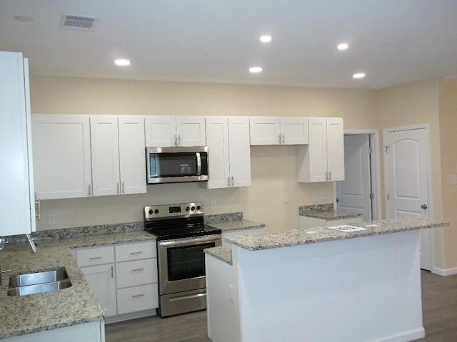 kitchen with a center island, sink, stainless steel appliances, and white cabinets