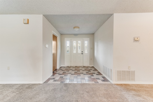 carpeted foyer featuring a textured ceiling