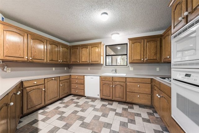 kitchen with white appliances, a textured ceiling, and sink