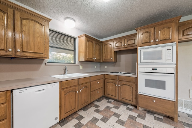 kitchen featuring a textured ceiling, sink, and white appliances