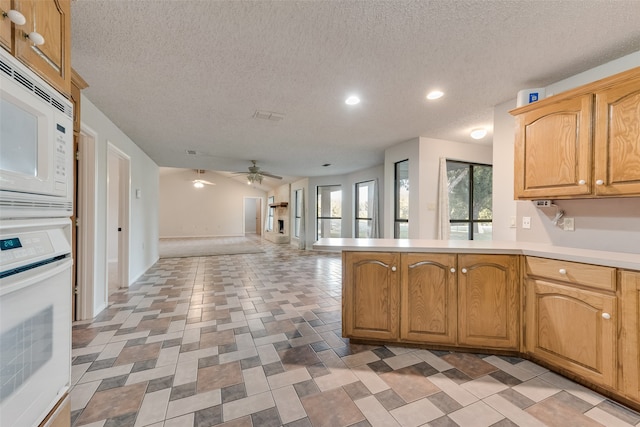 kitchen featuring kitchen peninsula, a textured ceiling, white appliances, and ceiling fan