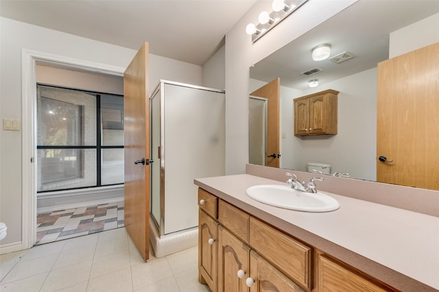 bathroom featuring vanity, toilet, tile patterned floors, and a shower with shower door