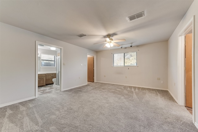 unfurnished bedroom featuring light colored carpet, connected bathroom, and ceiling fan