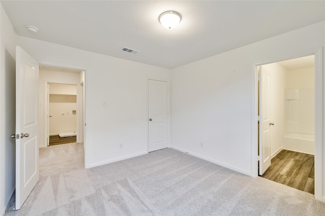 unfurnished bedroom featuring light colored carpet, a closet, and connected bathroom