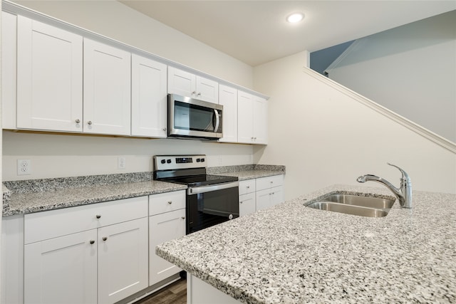 kitchen with light stone counters, sink, stainless steel appliances, and white cabinets