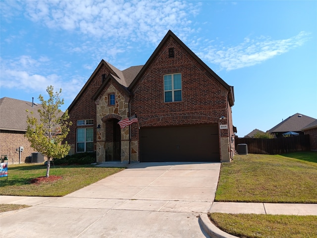 tudor home featuring central air condition unit, a front yard, and a garage