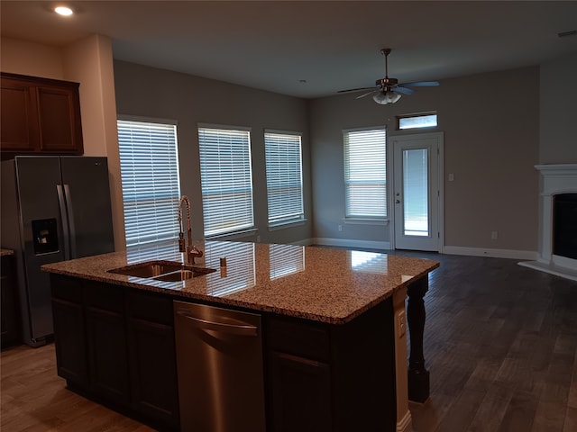 kitchen with ceiling fan, dark hardwood / wood-style flooring, sink, stainless steel appliances, and an island with sink