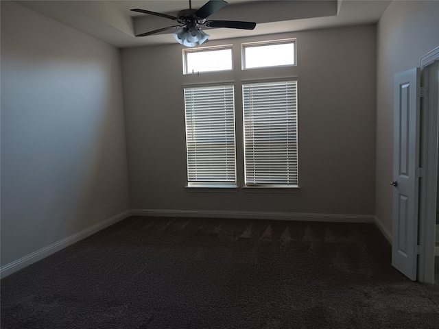 carpeted spare room with ceiling fan and a tray ceiling