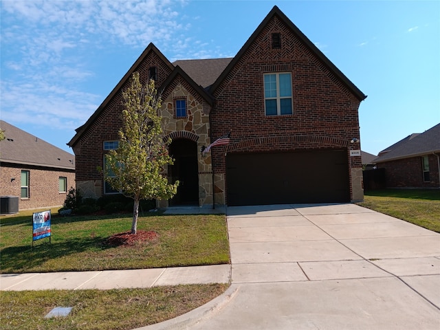 tudor home with a front yard, a garage, and central air condition unit