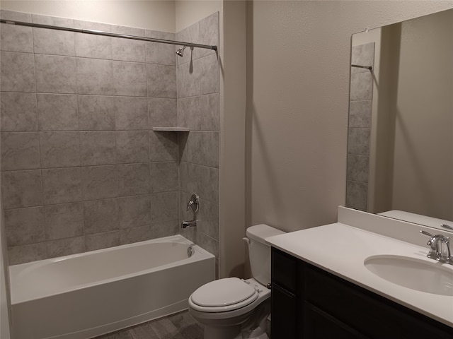 full bathroom with wood-type flooring, tiled shower / bath, vanity, and toilet