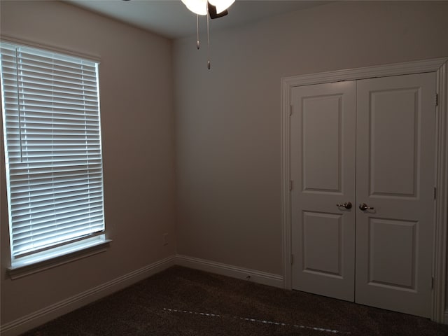 unfurnished room with dark colored carpet and ceiling fan