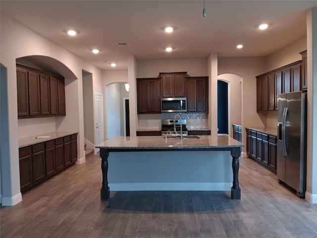 kitchen featuring an island with sink, appliances with stainless steel finishes, hardwood / wood-style floors, and sink