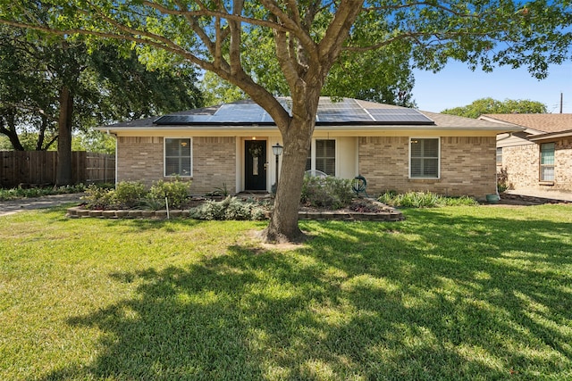 ranch-style home featuring a front lawn and solar panels