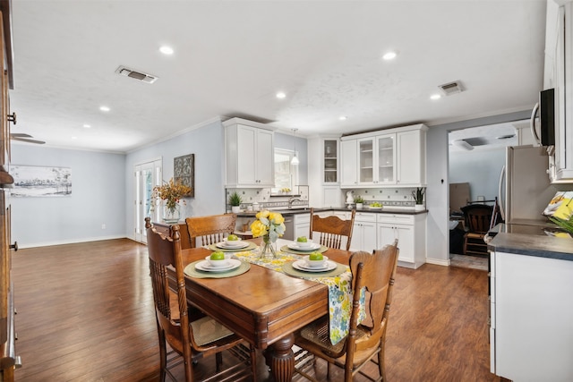 dining room with sink, dark hardwood / wood-style floors, and ornamental molding