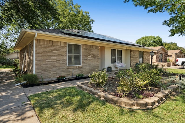 single story home with a front yard and solar panels