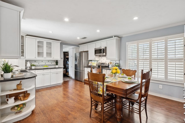 dining room with ornamental molding, sink, and hardwood / wood-style flooring