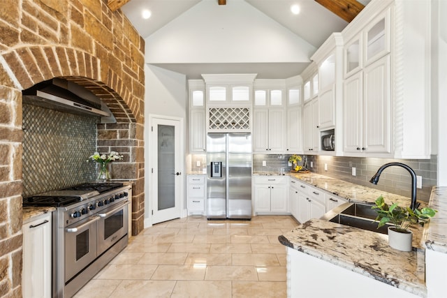 kitchen with light stone countertops, appliances with stainless steel finishes, tasteful backsplash, sink, and white cabinetry