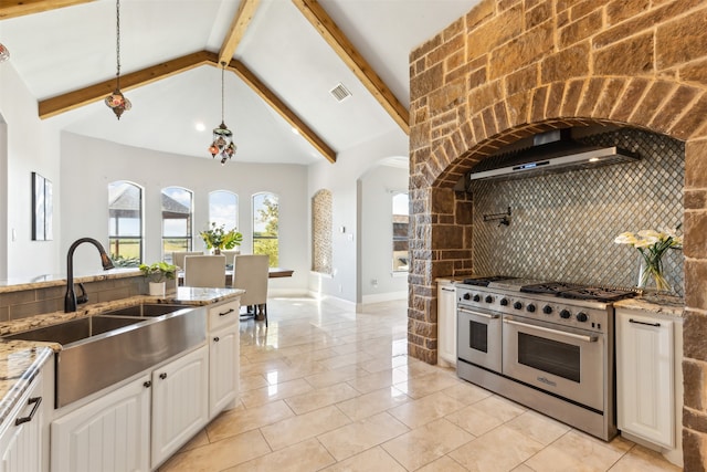 kitchen featuring light stone countertops, decorative backsplash, sink, lofted ceiling with beams, and range with two ovens