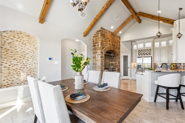 dining room featuring sink, high vaulted ceiling, and beamed ceiling