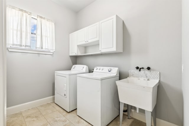 clothes washing area featuring separate washer and dryer, sink, and cabinets