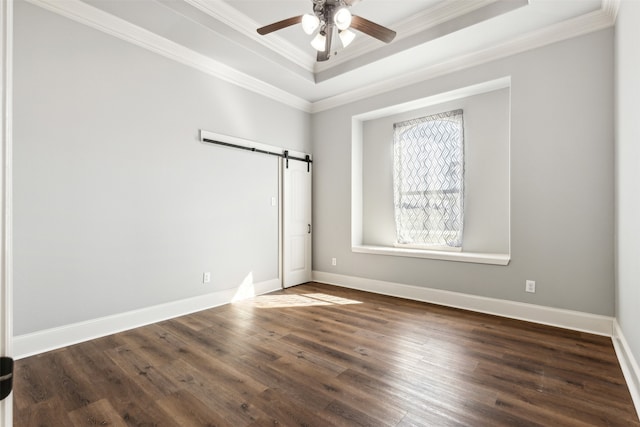 spare room with dark wood-type flooring, crown molding, and a barn door