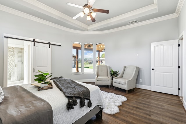 bedroom with ceiling fan, crown molding, dark wood-type flooring, a barn door, and connected bathroom