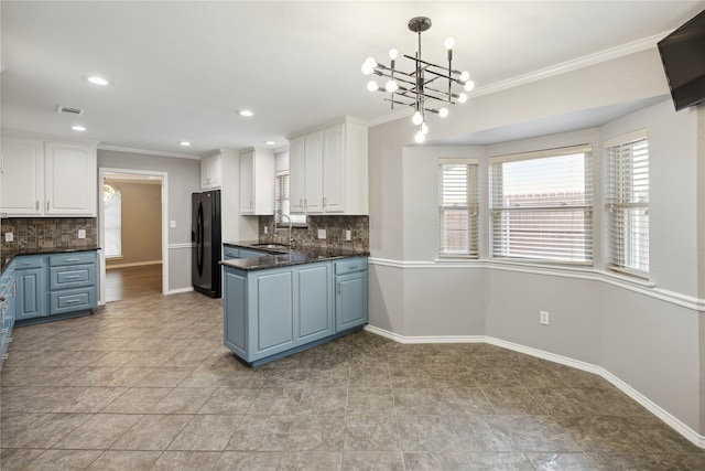 kitchen featuring decorative backsplash, black refrigerator, sink, decorative light fixtures, and white cabinetry