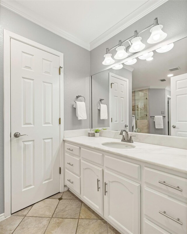 bathroom featuring tile patterned floors, vanity, a shower with door, and ornamental molding