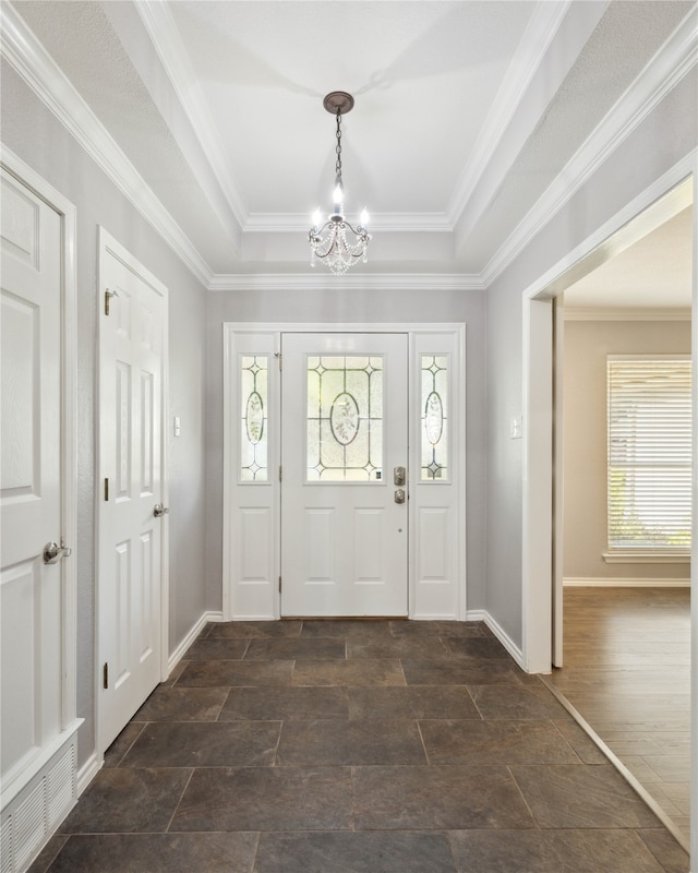 entryway featuring a healthy amount of sunlight, ornamental molding, and a tray ceiling