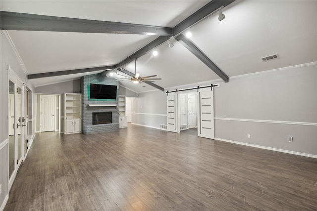 unfurnished living room featuring dark hardwood / wood-style flooring, ceiling fan, lofted ceiling with beams, a barn door, and a fireplace