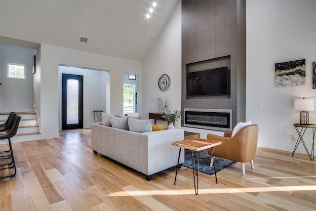 living room featuring light hardwood / wood-style floors, a fireplace, and high vaulted ceiling