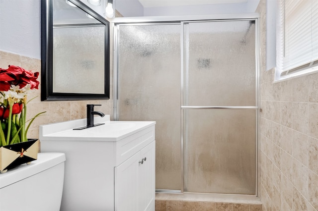 bathroom with tile walls, vanity, toilet, and an enclosed shower