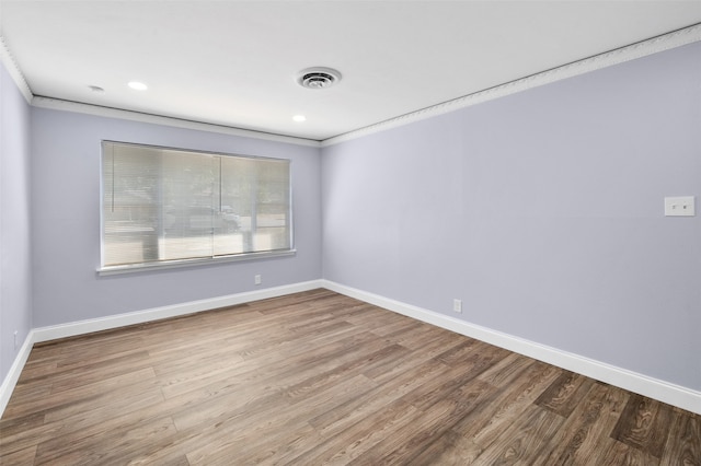 empty room with ornamental molding and hardwood / wood-style flooring