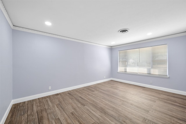 empty room with wood-type flooring and ornamental molding