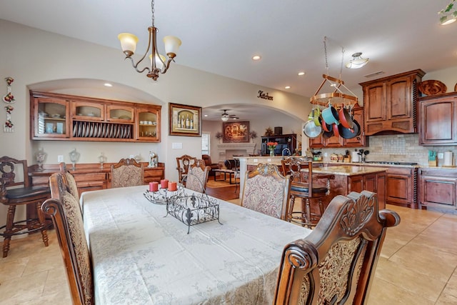 tiled dining space featuring ceiling fan with notable chandelier